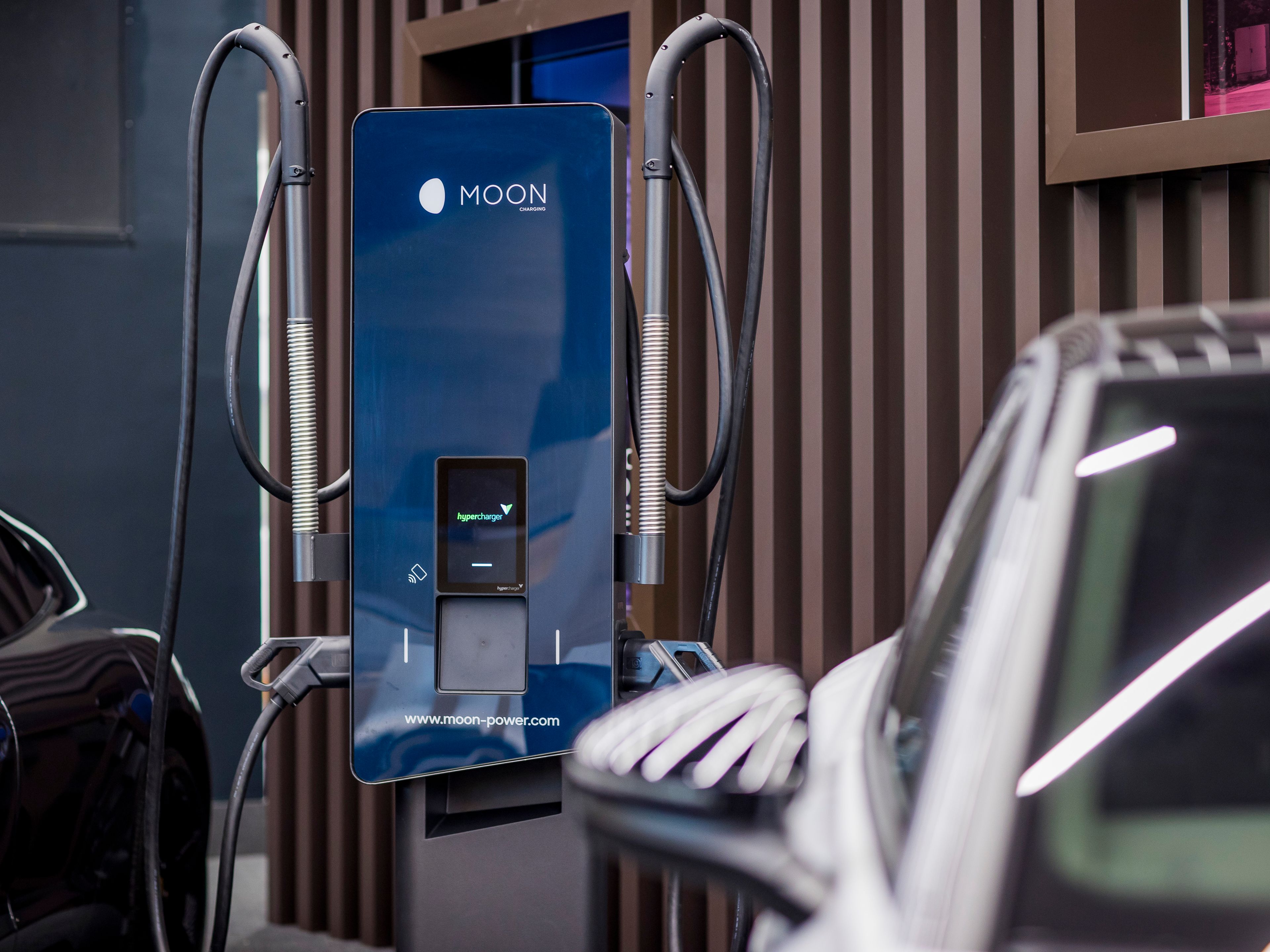 Električno vozilo parkirano ob hitri polnilni postaji v urbanem okolju.