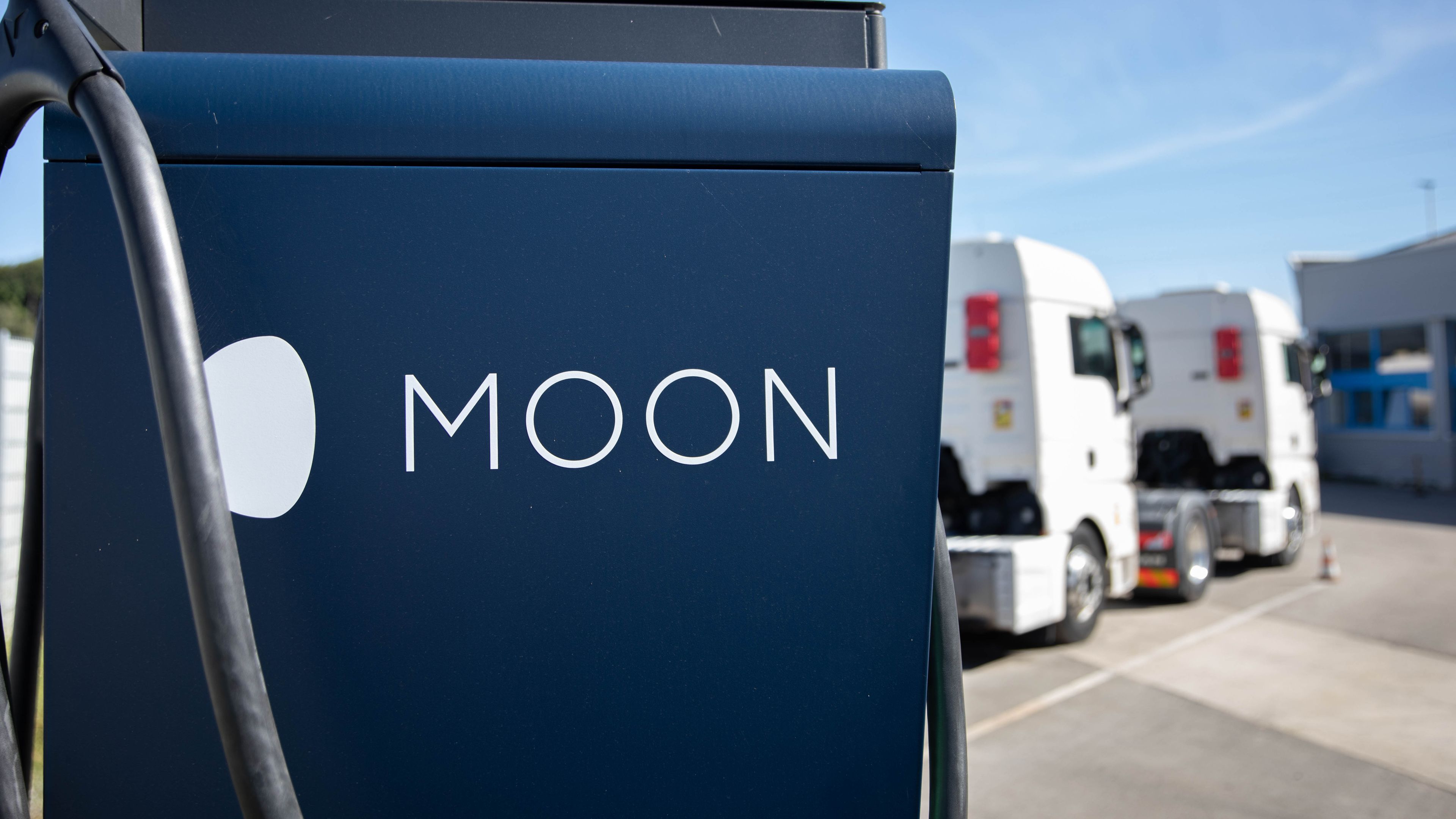 Dva tovornjaka sta parkirana za MOON HYC 200–400 hitro polnilno postajo.