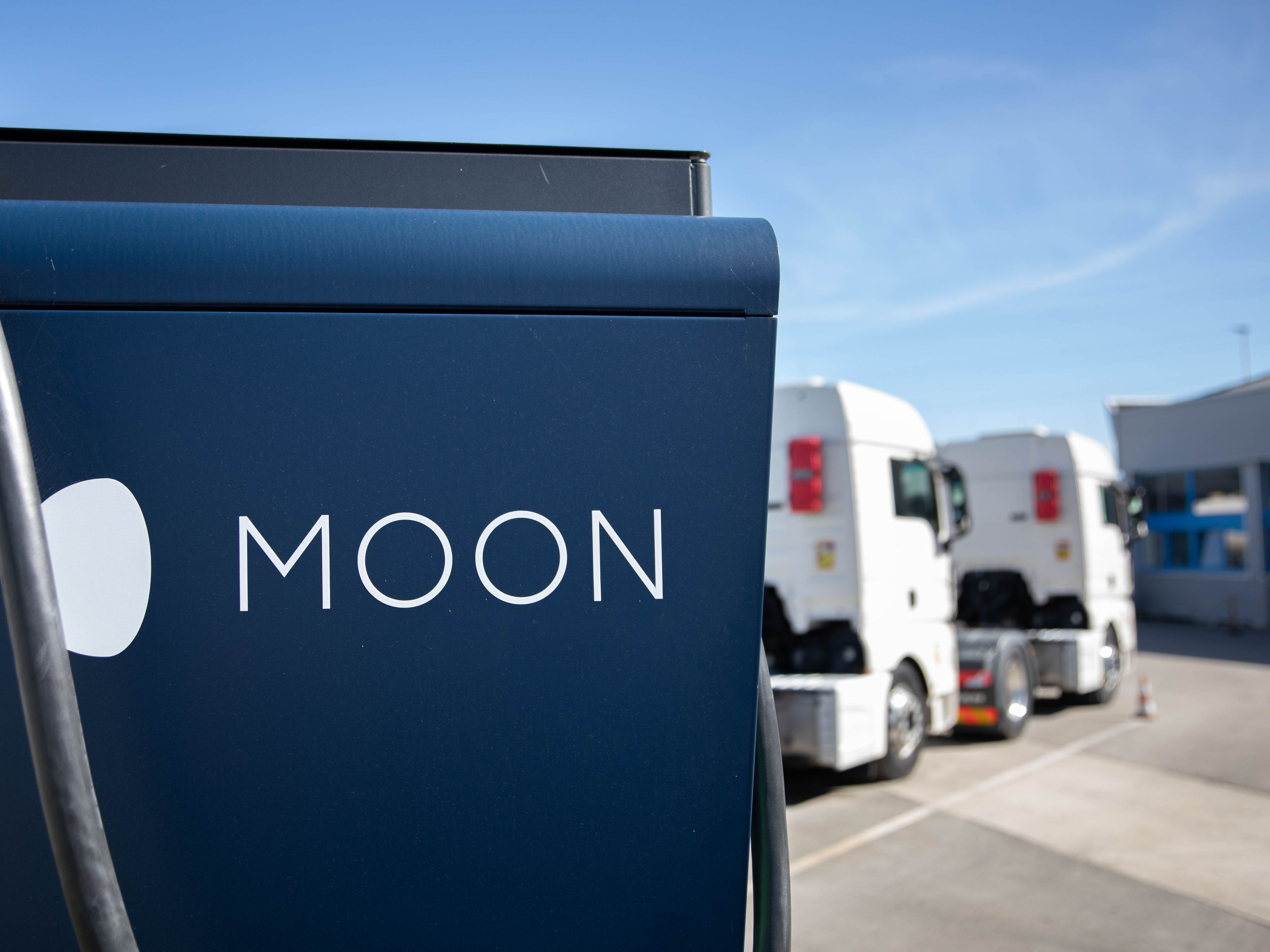 Dva tovornjaka sta parkirana za MOON HYC 200–400 hitro polnilno postajo.