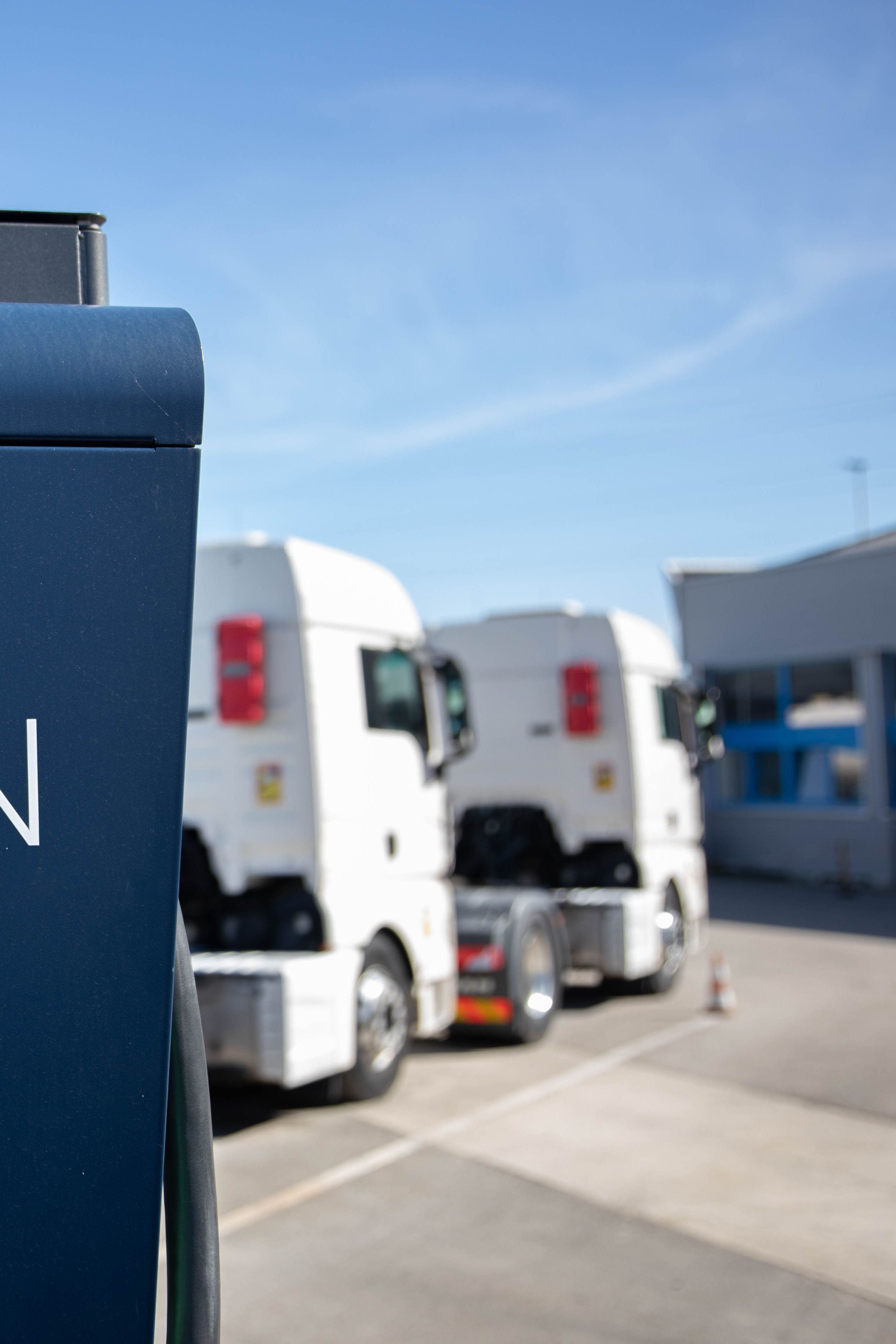 Dva tovornjaka sta parkirana za MOON HYC 200–400 hitro polnilno postajo.