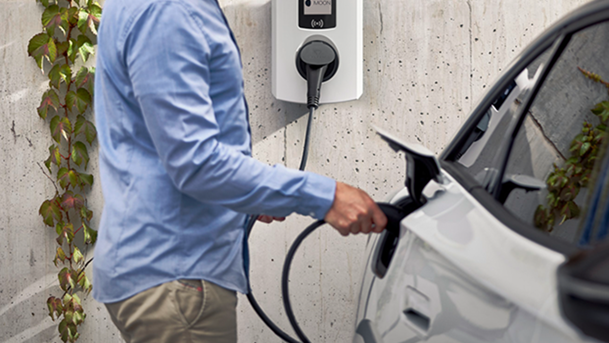 Moški polni električni avto s stensko polnilno postajo