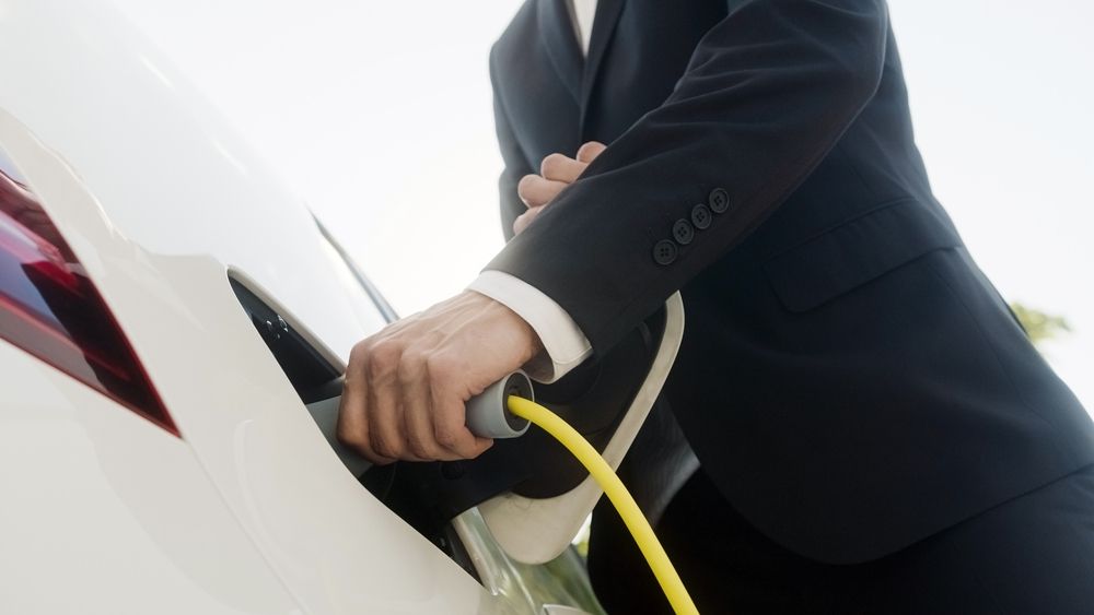 Moški je priklopil električni avtomobil