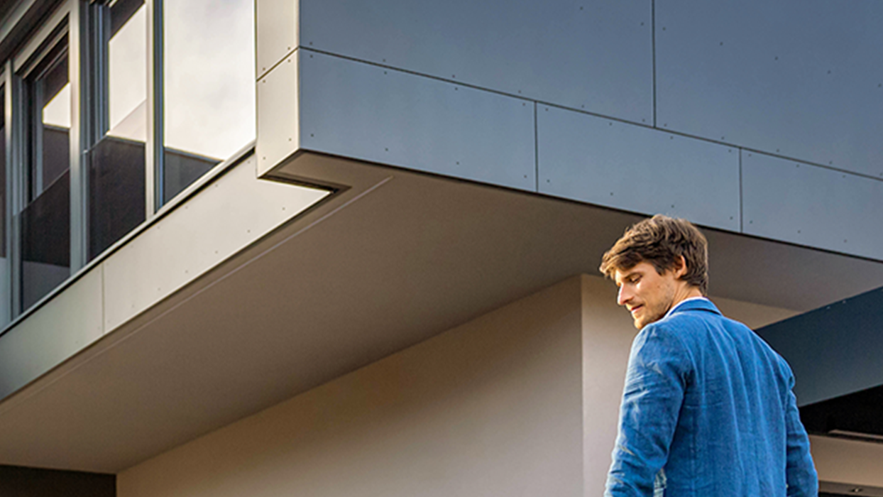 Oseba hodi proti električnemu avtomobilu s kablom v roki